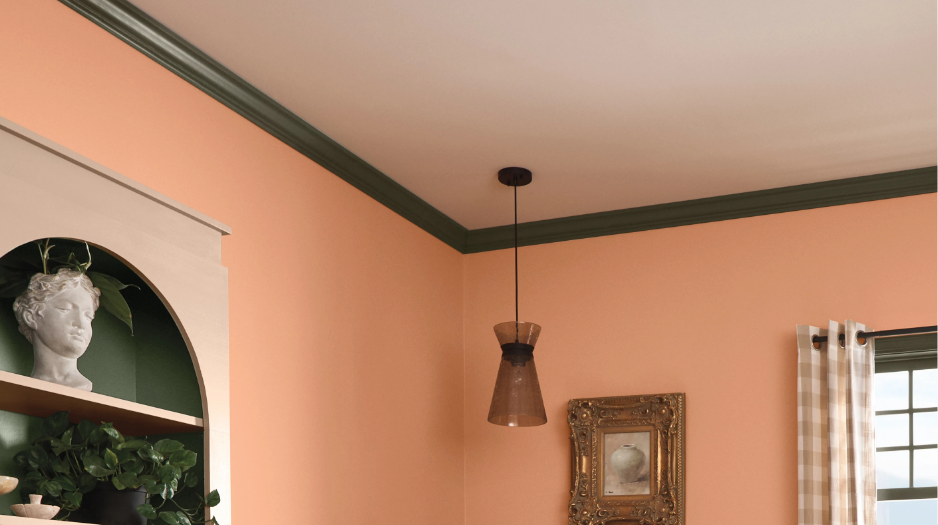 Corner of a living room ceiling painted white with green molding, pendant light hanging, walls painted mauve.