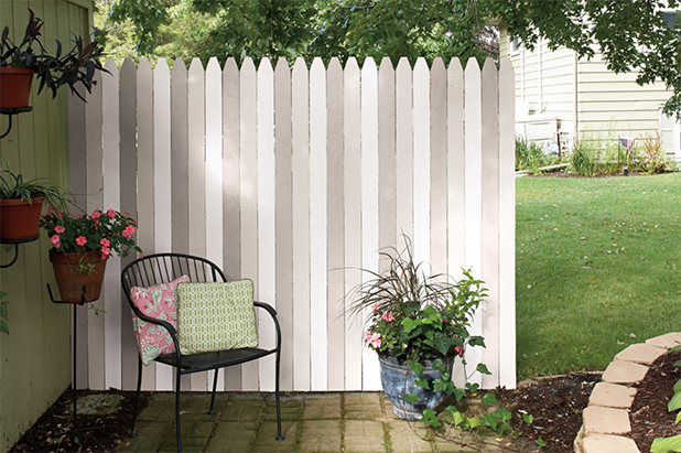 Back patio, small accent chair and pillows, with picket fence painted three alternating colors of white, off-white and grey.