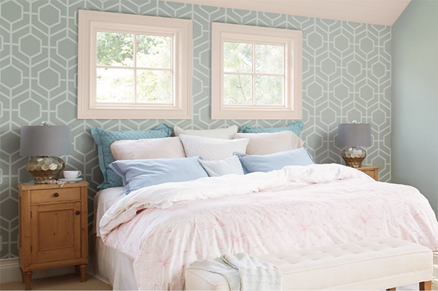 A bedroom features a stenciled geometric pattern in white on a light teal wall.