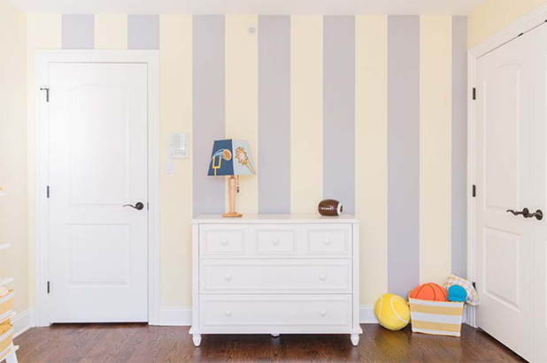 Child’s room with white door, closet door and dresser. A lamp and football on the dresser with a striped accent wall.