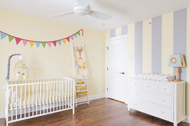 Child’s room with white door, closet door and dresser. A lamp on the dresser with a striped accent wall.