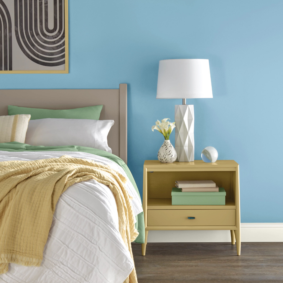 Bedroom with artwork on a wall that is painted in the color superhero blue.