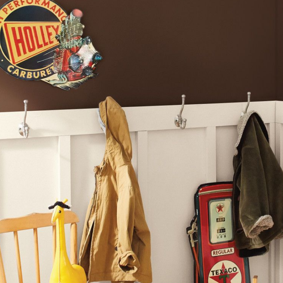 Mudroom with coats hanging on hooks and retro gas station signage. Wall is painted ground coffee.