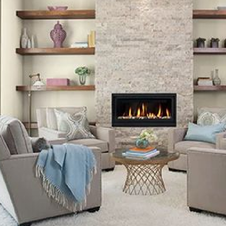 Cozy living room with accent chairs, a fire in the fireplace and well-curated bookshelves. Wall color is weathered rock gray.