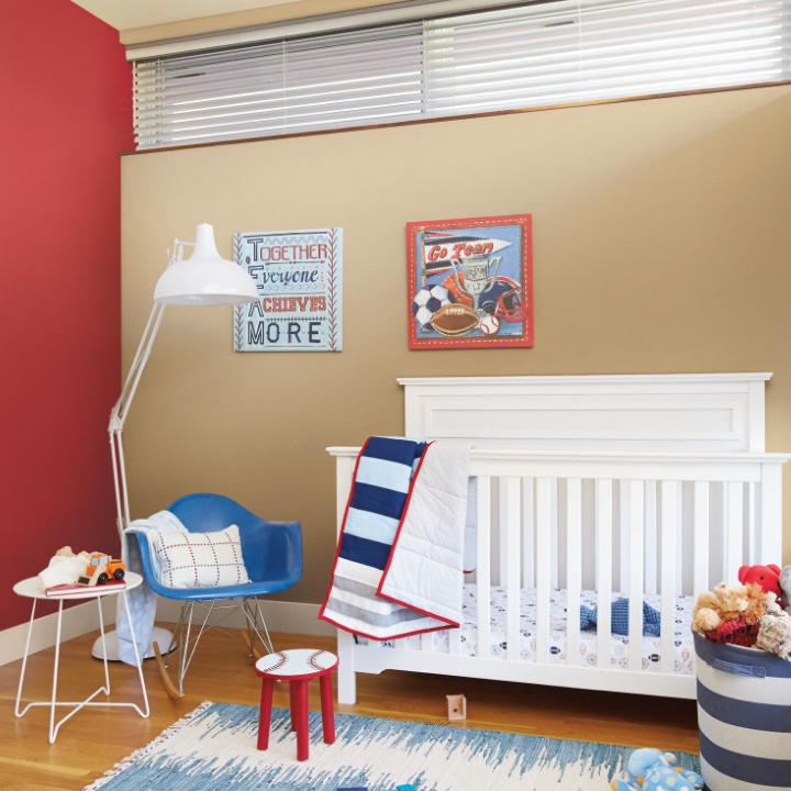 Nursery with large crib, sitting chair, side table and blankets. Wall painted the color Suncoast.