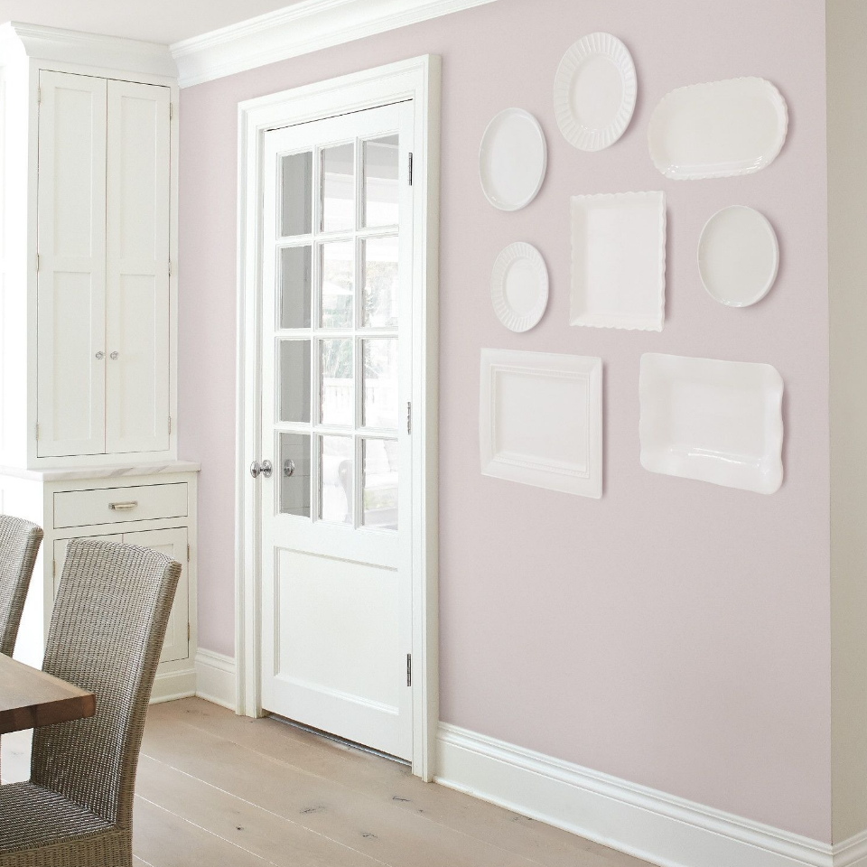 Bright dining room with white plates and platters mounted on a chalky purple wall.