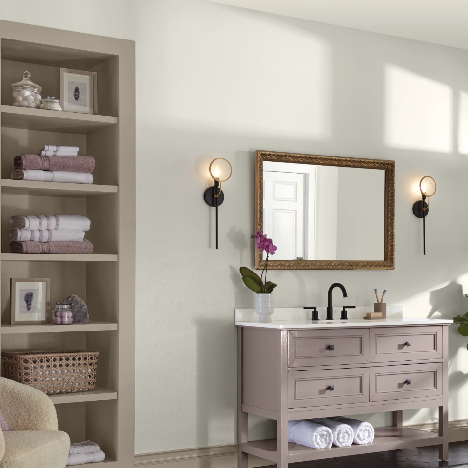 Ultra White bathroom, farmhouse-style vanity with mirror and modern sconces. Shelving holds towels and toiletries.