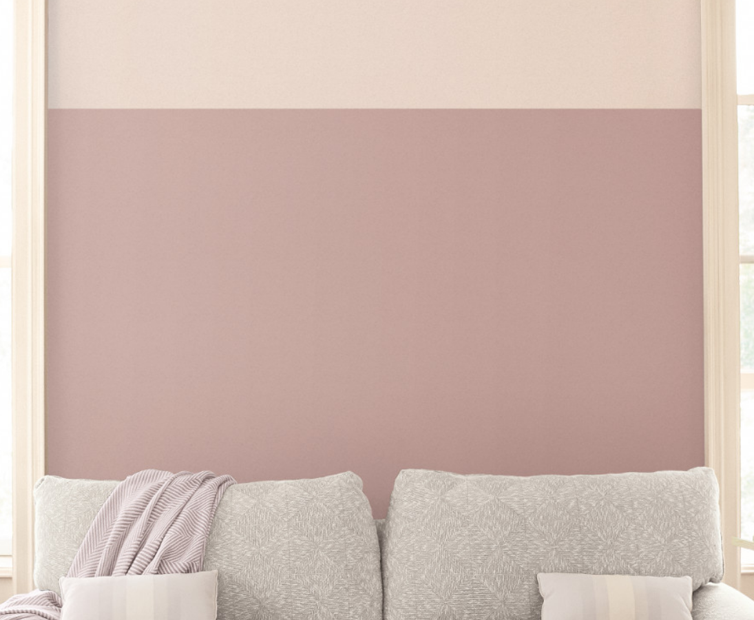 A color-blocked wall – mauve and beige – sits behind a cozy looking loveseat.