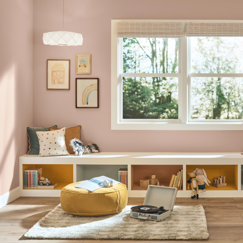 A sunny indoor children’s playroom with built-in bench. Walls are painted neutral mauve mystery.