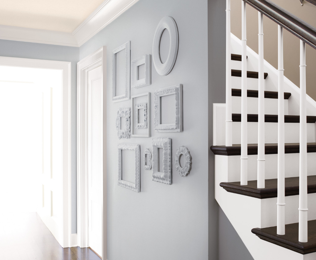 Hallway painted silvery gray has a gallery of unique shaped empty picture frames, painted in the same color silvery gray.