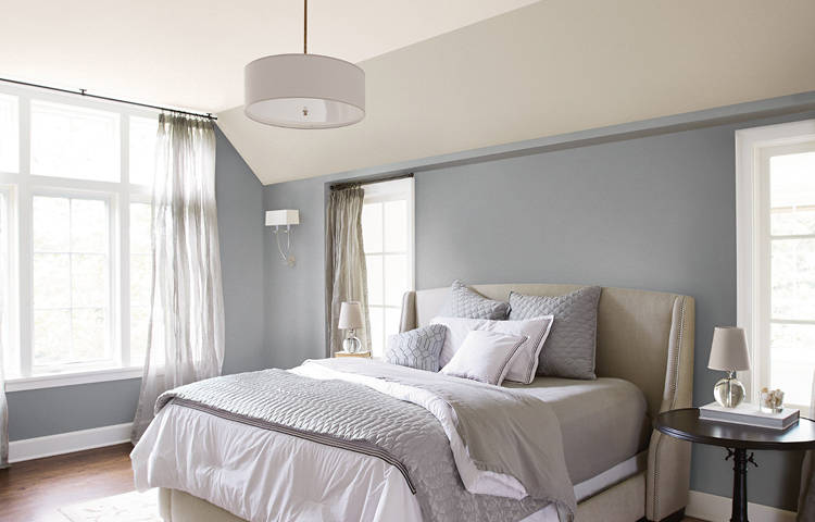 A plush king size bed in a calming bedroom, with ironed gray on the walls.