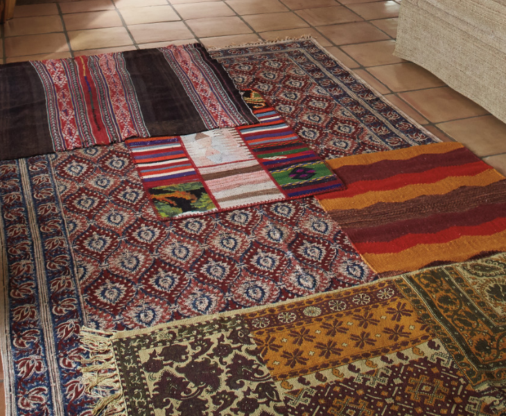Layered throw rugs over a larger area rug provide an eclectic tapestry on a living room floor.