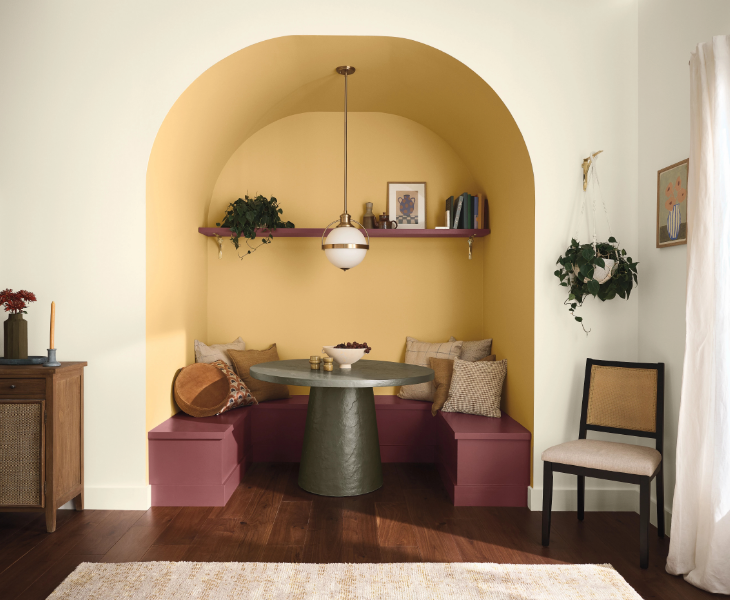 A breakfast nook, beautifully styled with a modern table and strawberry fields painted bench. Walls are yellow.
