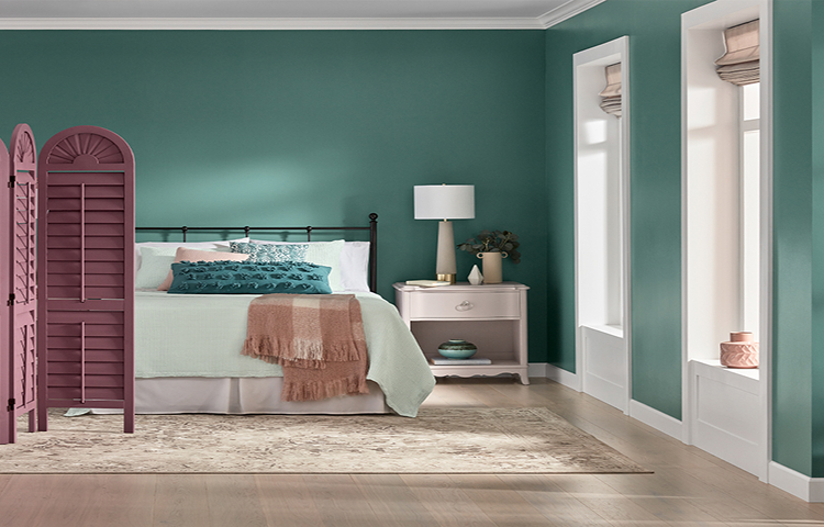 Sunlit, deep-aqua bedroom, bed with matching linens and a light pink side table and lamp, mauve temporary privacy wall.