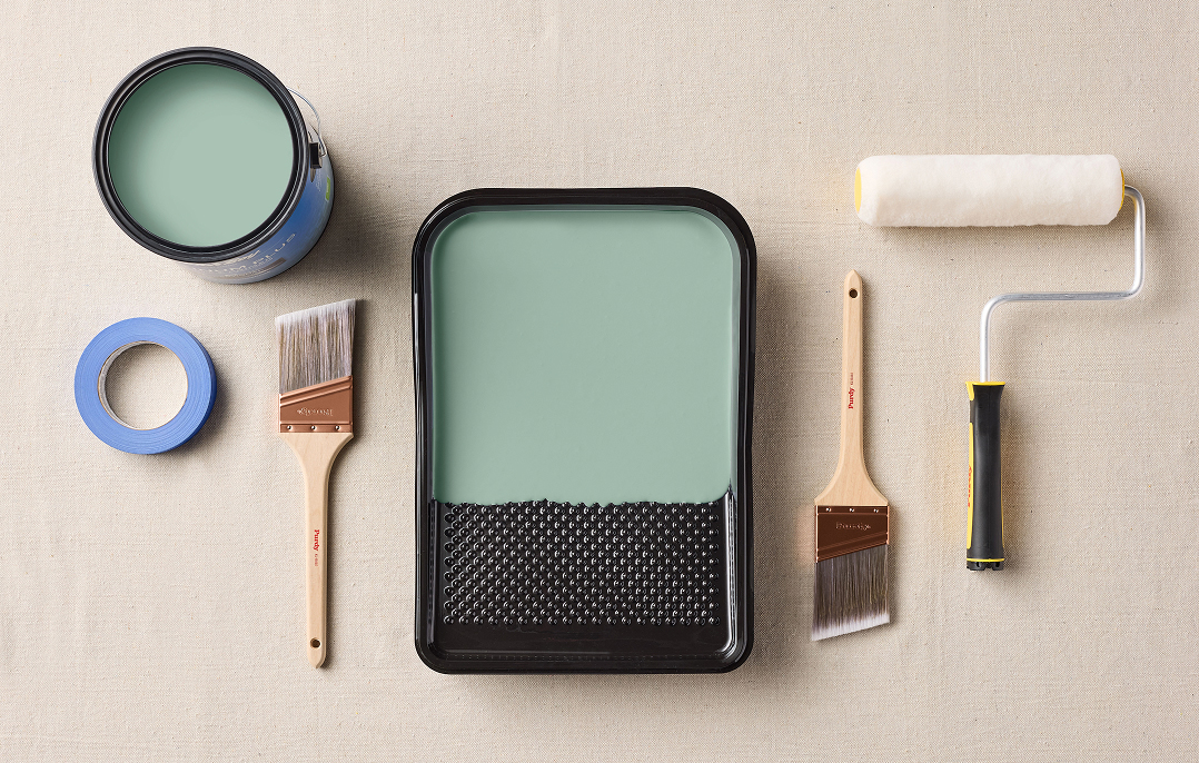 A gallon container of Dutch Boy Paint, paint tray and assorted painting tools.