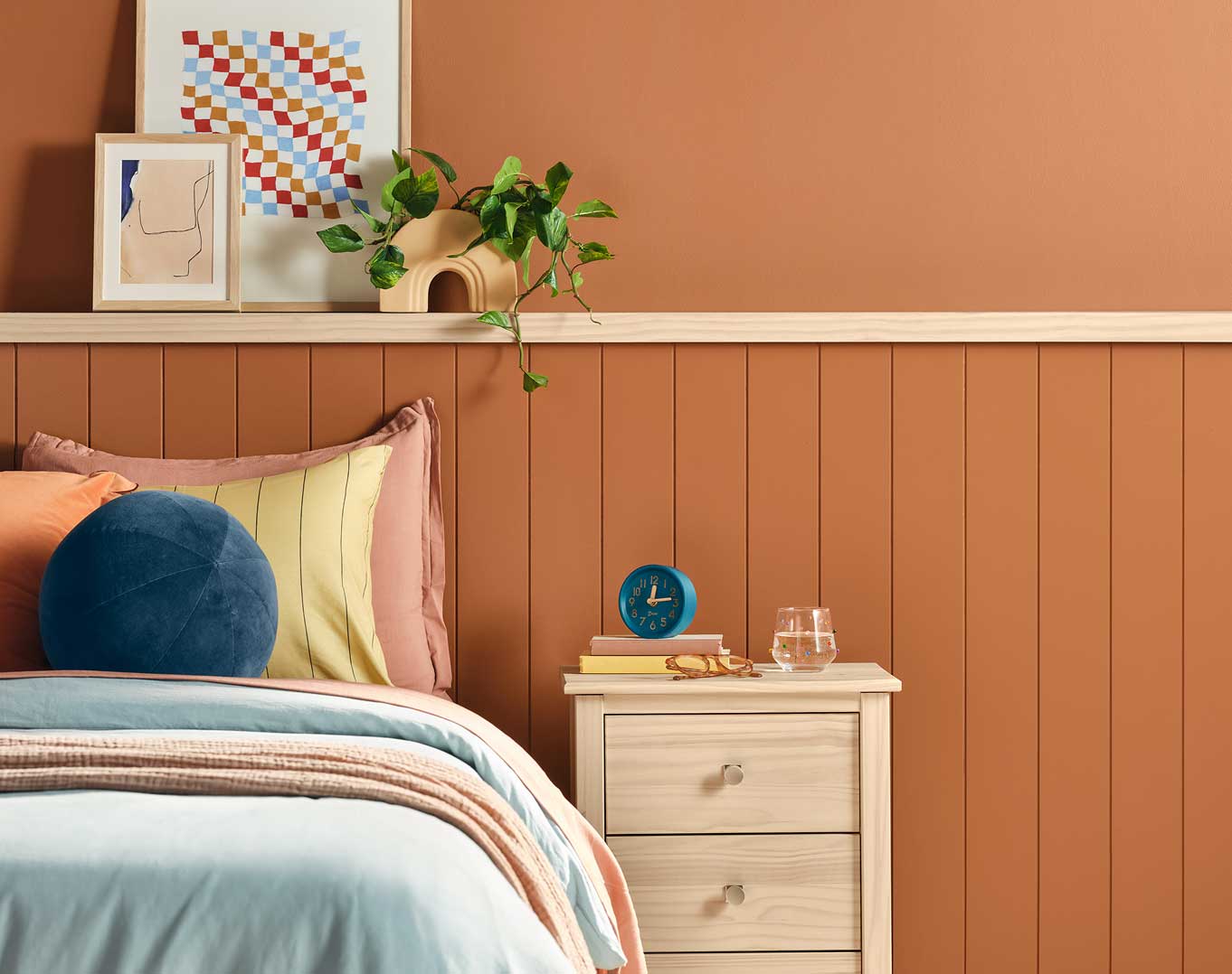 A bedroom wall painted in Deep Rooted with a bed and nightstand.
