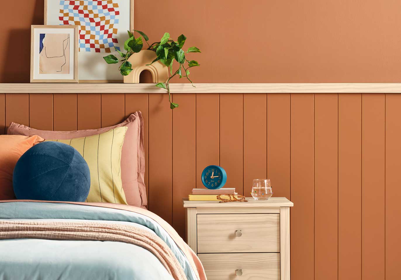 A bedroom wall painted in Deep Rooted with a bed and nightstand.