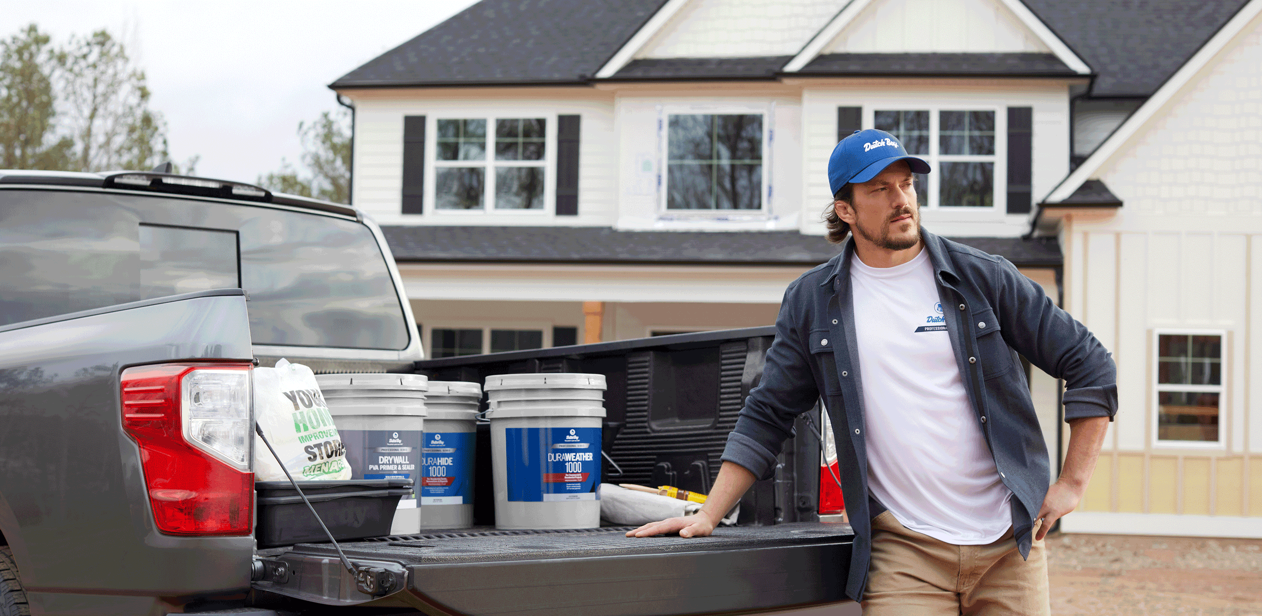 Pro standing by truck tailgate with 5-gal buckets of Dutch Boy paint