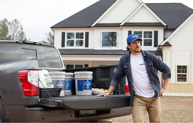 Pro standing by truck tailgate with 5-gal buckets of Dutch Boy paint