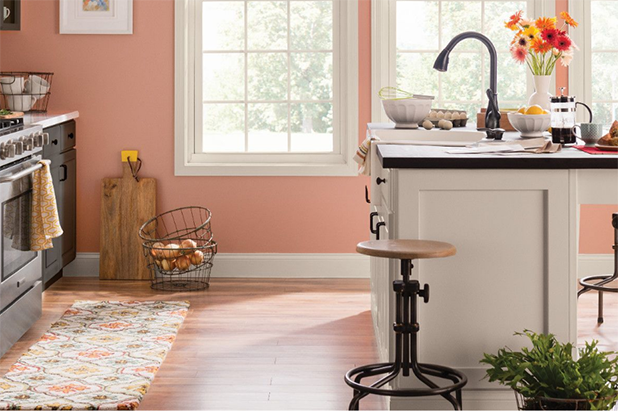 Brightly lit kitchen with island that has white cabinets and dark countertop. Walls painted native copper.