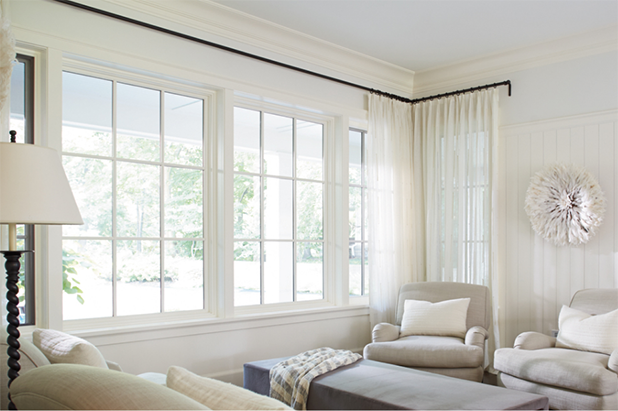 Sunny front room with large, framed windows, cozy accent chairs, a coffee table and white walls.