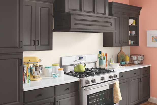 A kitchen stove top and range in white with a green tea kettle. Backsplash is painted in a light-colored semi-gloss paint.