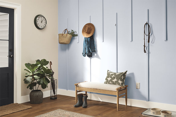 Mudroom with coats hanging on hooks and retro gas station signage with a brown colored wall and white wainscotting. 