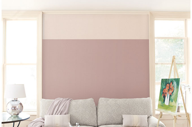 Living room with couch, side table and canvas on easel painting, with a dual-painted wall behind the couch.