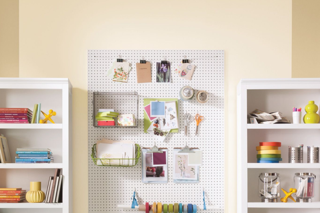 painted pegboard on wall surrounded by bookcases