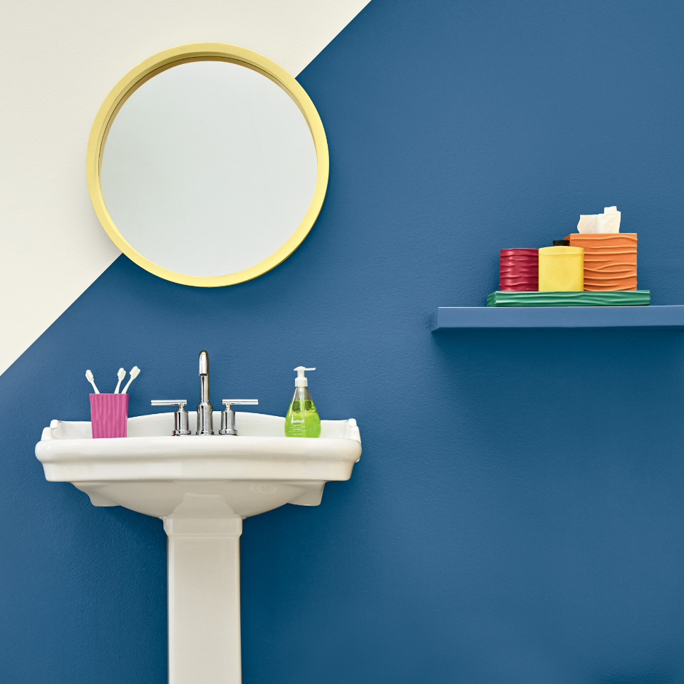 Bathroom vanity with a gold-framed mirror and shelving. Wall painted in the colors off white and ribbon blue.