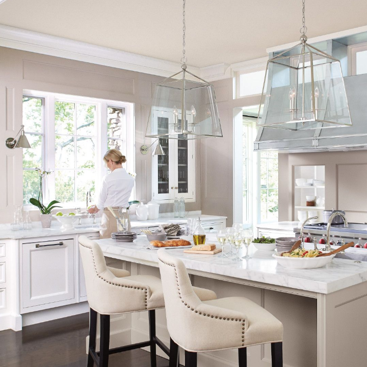 A large, luxurious kitchen with high ceilings and a grand kitchen island with walls that feature sultry gray. 