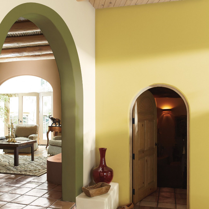 Large, Santa Fe style living space, with an arched doorway opening to a living room. Walls painted exotic yellow.