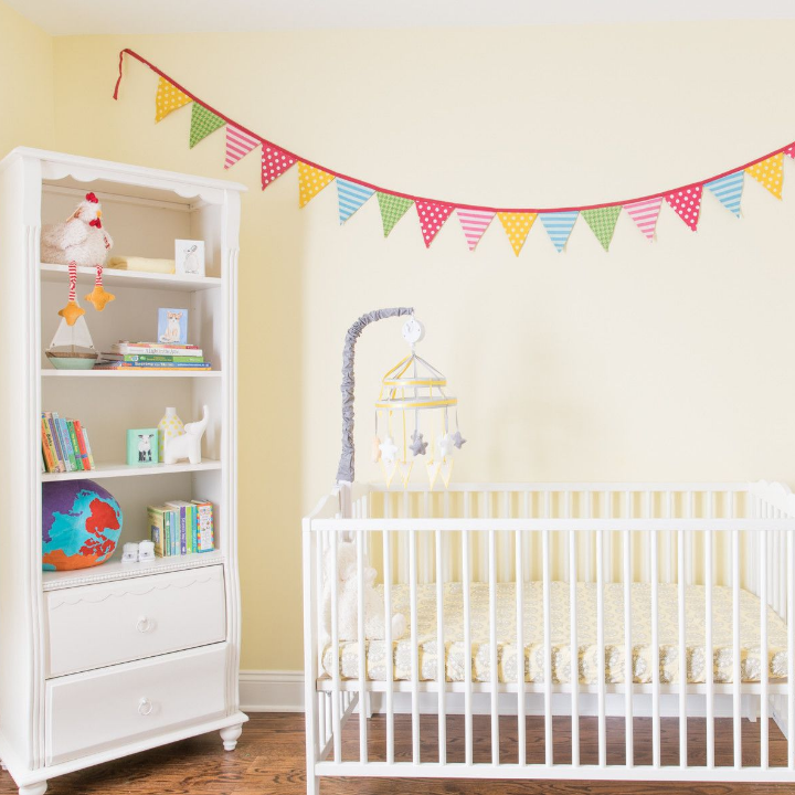 yellow walls in a baby's bedroom with crib and bookshelf