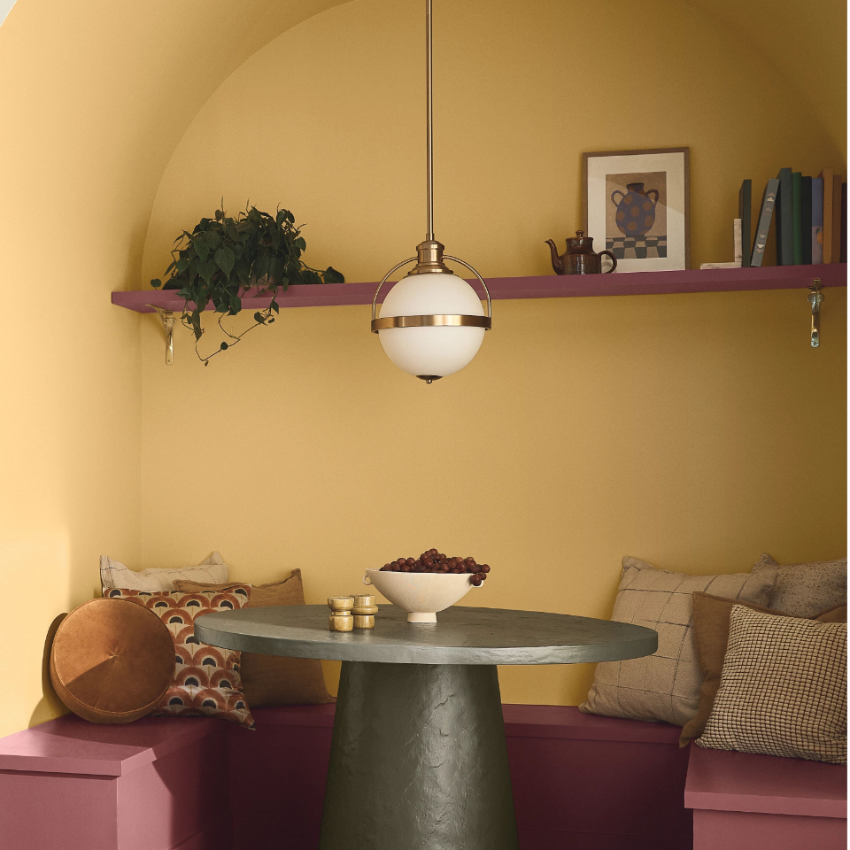 A breakfast nook, with a modern table and built-in bench. Walls are painted in  pineapple flan.