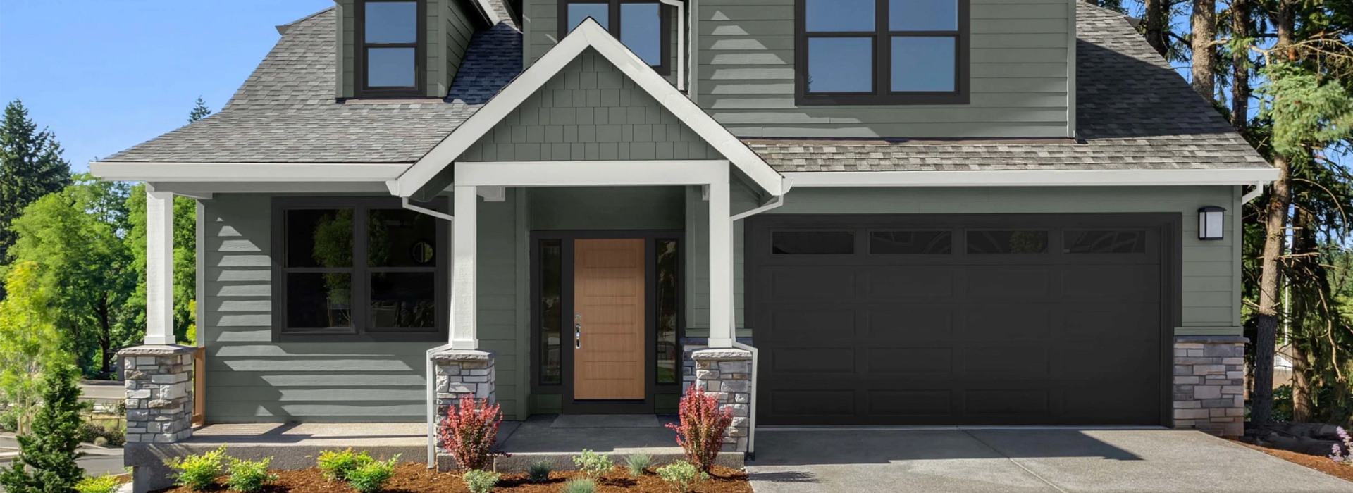 Front of a newly built and landscaped craftsman-style house, painted with Antiquated Pewter color with a concrete driveway.