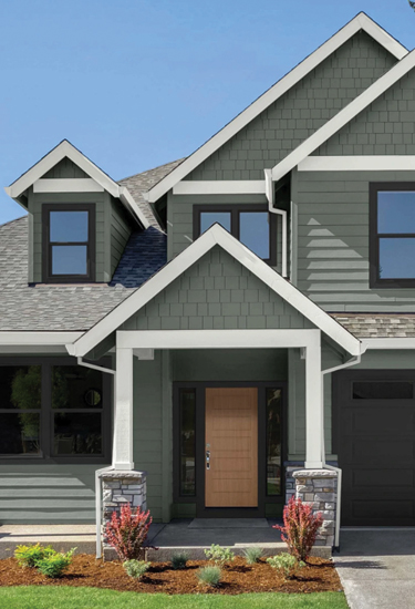 Front of a newly built and landscaped craftsman-style house, painted with Antiquated Pewter color with a concrete driveway.