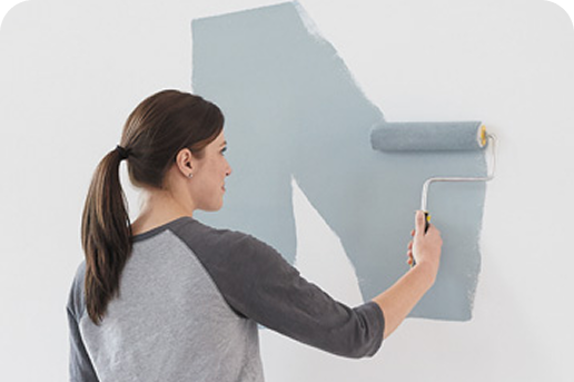 Woman painting a white wall with a muted blue paint using a Purdy paint roller.