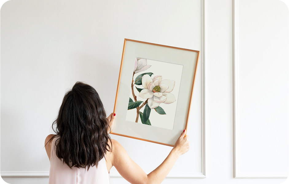 Woman taking heavy artwork off a white wall with wainscoting showing no scuffing or scratches are left behind.