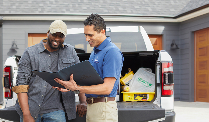 Contractor and Dutch Boy Professional Series Field Rep talking together in front of truck full of painting supplies, next to a residential home.