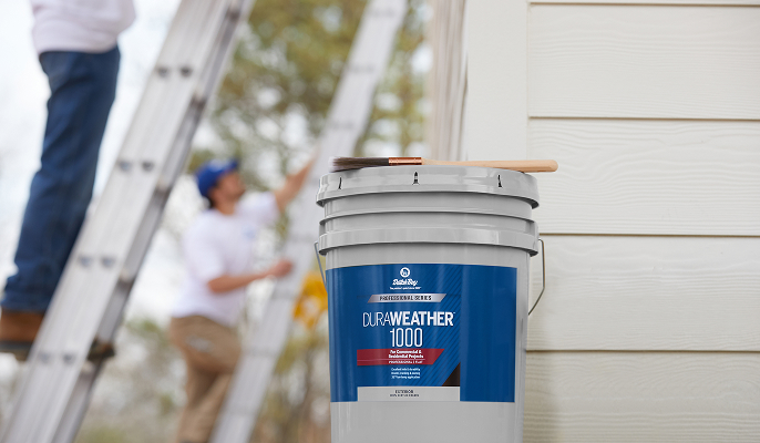 Professional painter on ladders with a 5 gallon bucket of Dutch Boy paint