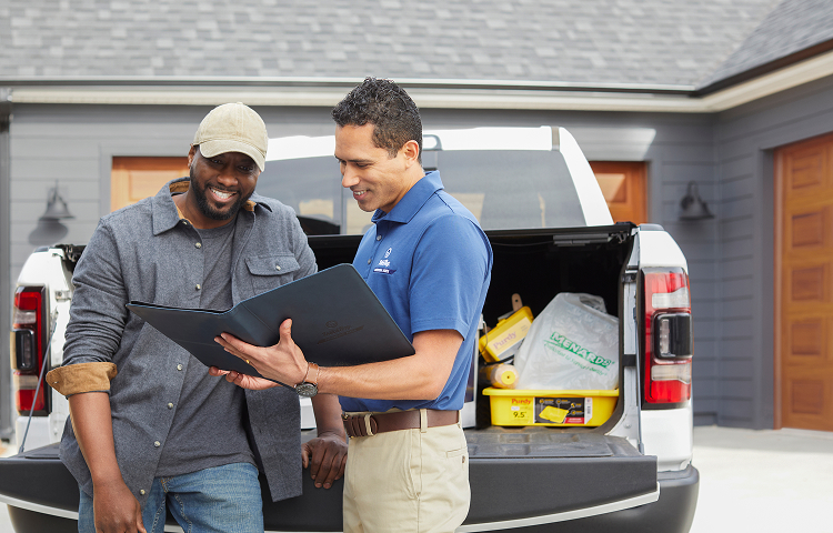 Contractor and Dutch Boy Professional Series Field Rep talking together in front of truck full of painting supplies, next to a residential home.