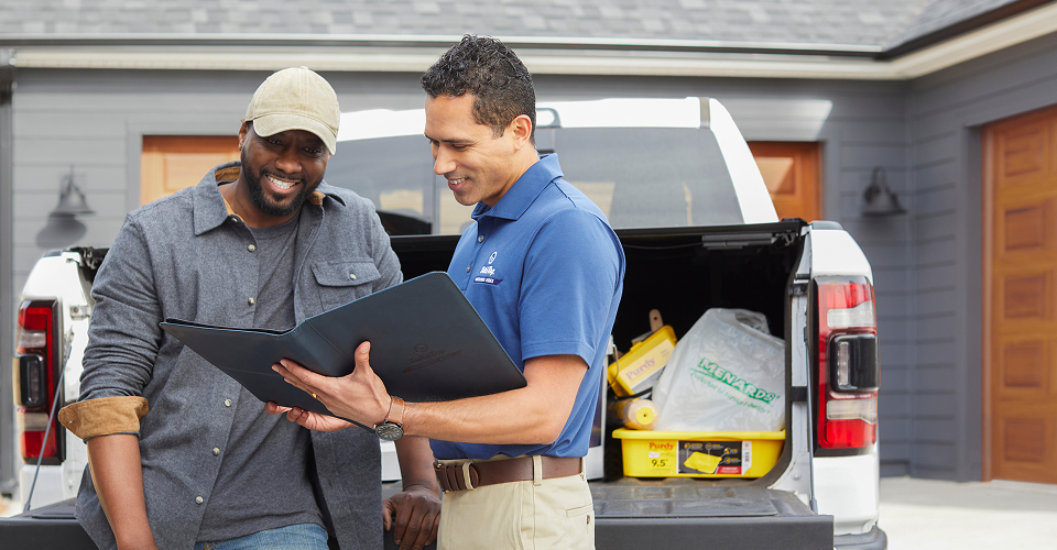 Contractor and Dutch Boy Professional Series Field Rep talking together in front of truck full of painting supplies, next to a residential home.