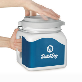 A one-gallon can of paint is held by the handle with one hand and the top is twisted by the other hand.