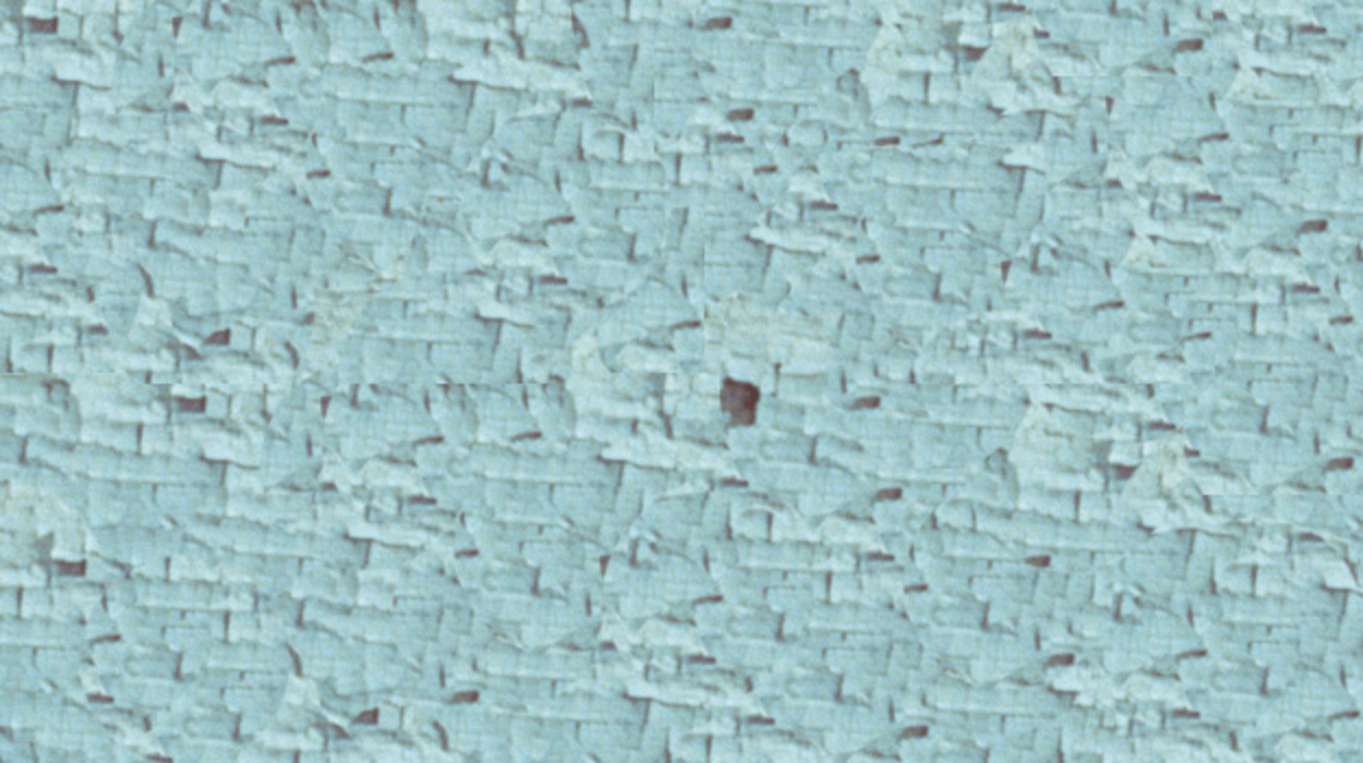 A wall painted light blue long ago is showing signs of delamination.