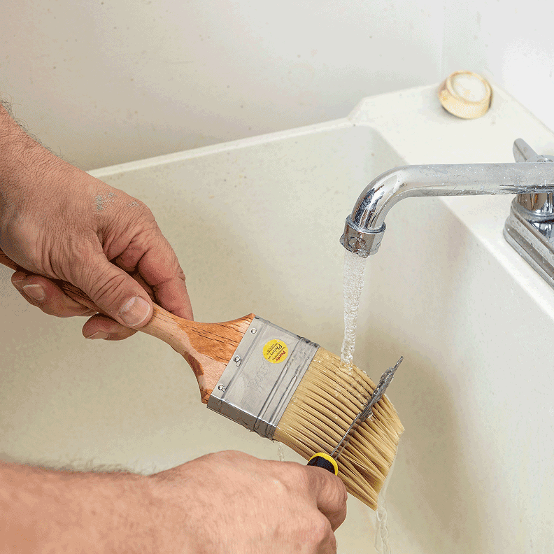 Person cleaning a brush in a utility sink