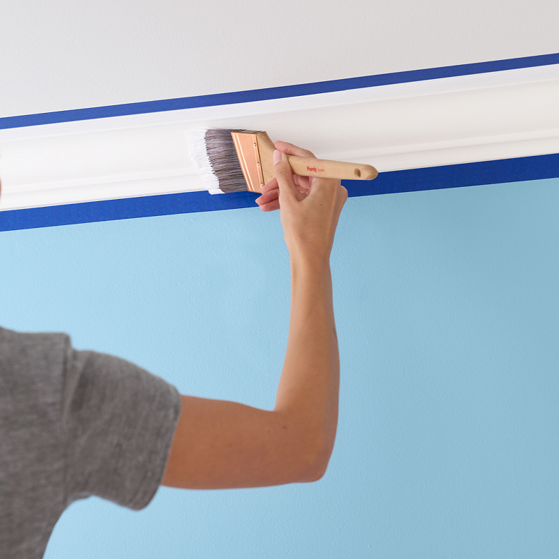 Person applying paint to crown molding.