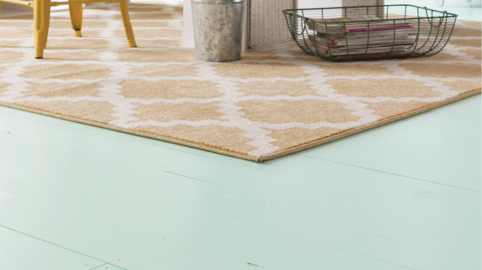 A lived-in kitchen with the floor painted light blue, yellow patterned area rug.